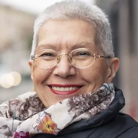 Senior woman with short hair smiling outdoors in the winter.